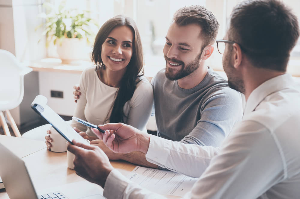 Couple en consultation avec un professionnel de santé, souriant et attentif, représentant l’accompagnement personnalisé dans le parcours de soin en AMP (Assistance Médicale à la Procréation).